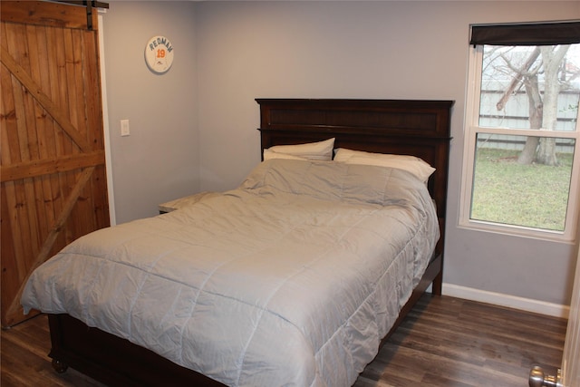 bedroom with a barn door and dark hardwood / wood-style flooring