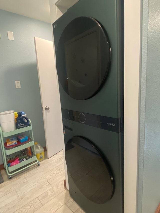 laundry area featuring stacked washer / drying machine and light hardwood / wood-style flooring