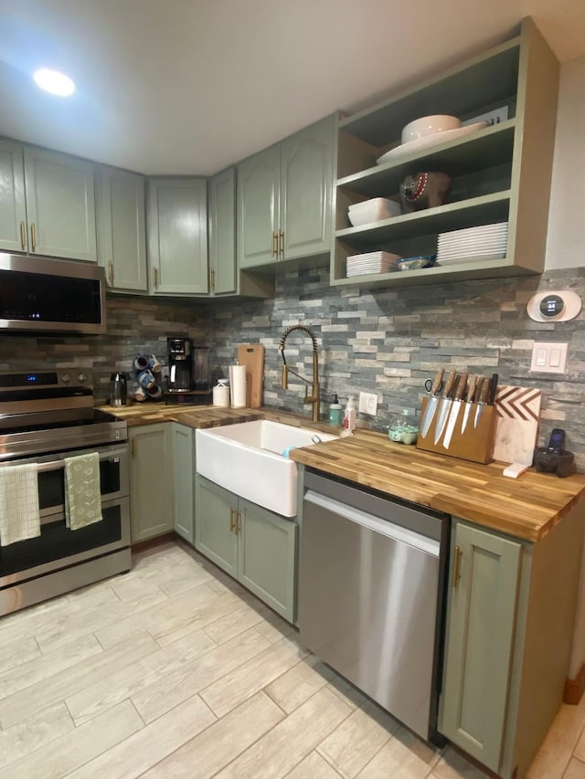 kitchen with butcher block countertops, sink, appliances with stainless steel finishes, tasteful backsplash, and green cabinetry