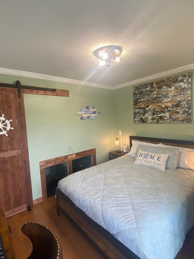 bedroom with hardwood / wood-style flooring, ornamental molding, and a barn door