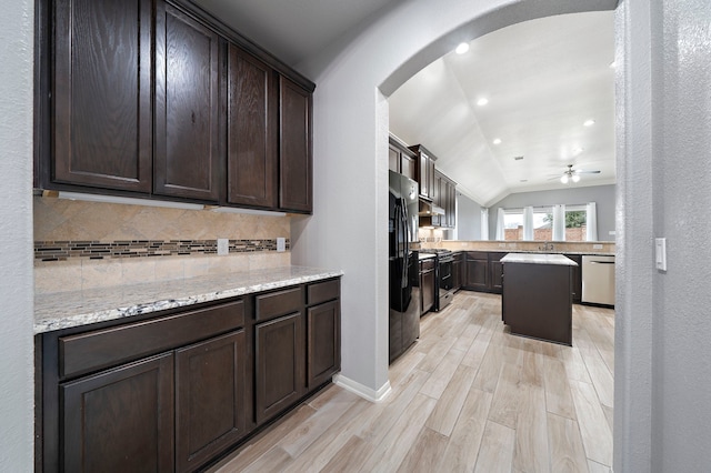 kitchen with dark brown cabinetry, lofted ceiling, tasteful backsplash, light stone counters, and stainless steel appliances