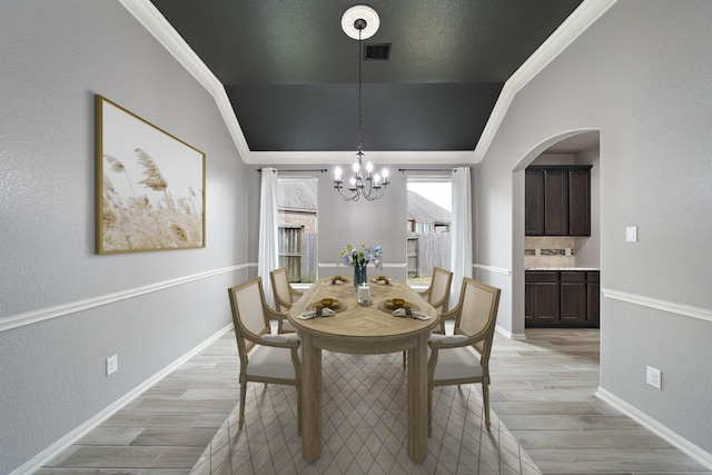 dining room featuring crown molding, lofted ceiling, and a notable chandelier