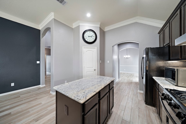 kitchen with a center island, light stone counters, gas stove, crown molding, and light hardwood / wood-style flooring