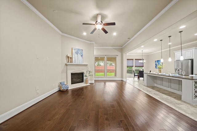 unfurnished living room featuring hardwood / wood-style flooring, ornamental molding, and ceiling fan with notable chandelier