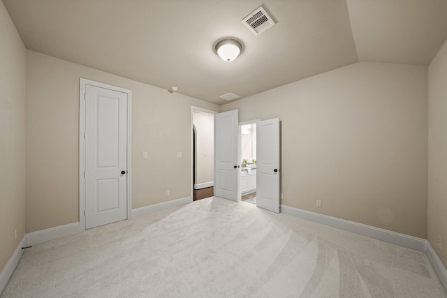 unfurnished bedroom with vaulted ceiling and light colored carpet