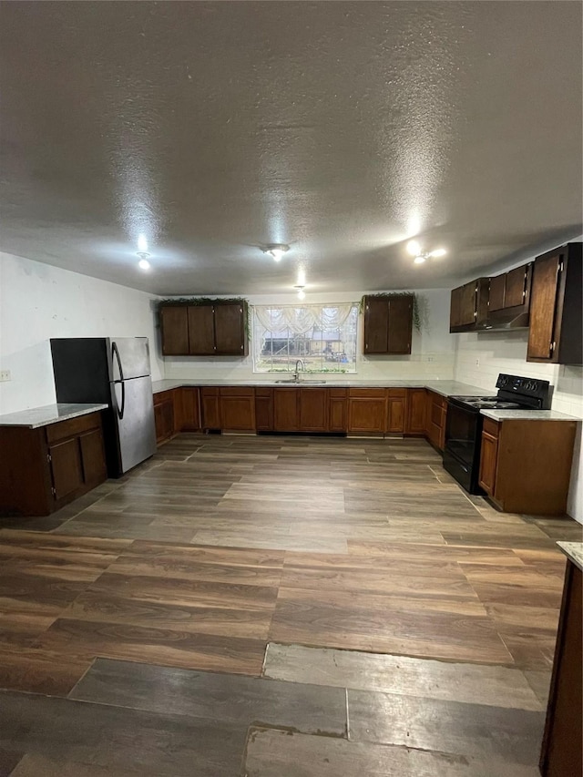 kitchen featuring black electric range, sink, a textured ceiling, and light hardwood / wood-style flooring