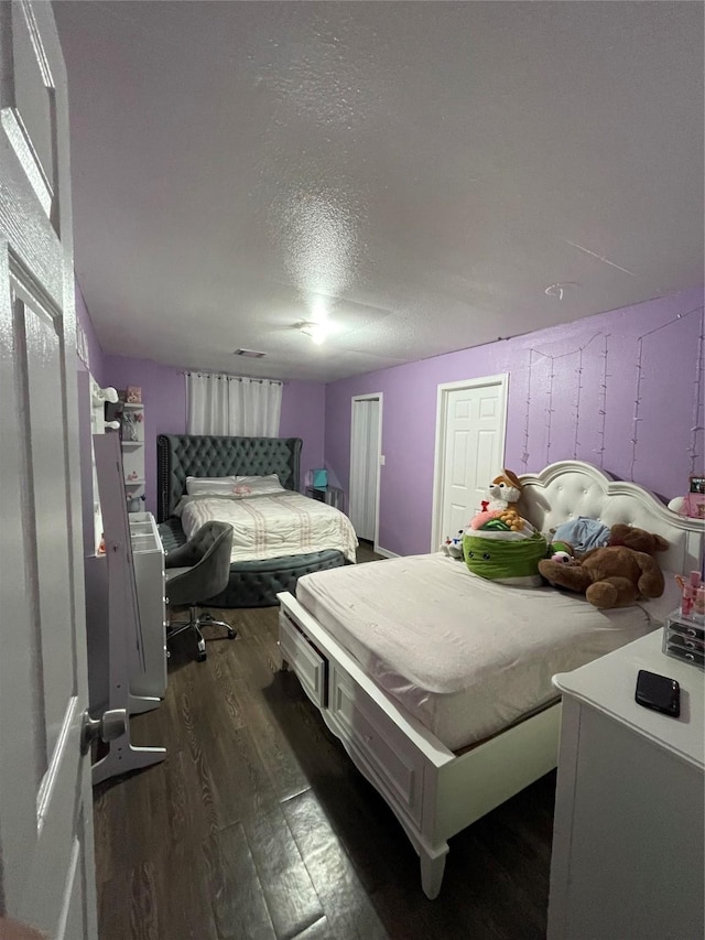 bedroom featuring dark hardwood / wood-style flooring and a textured ceiling