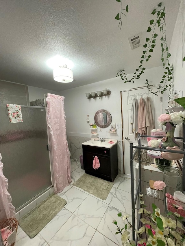 bathroom with vanity, a textured ceiling, and walk in shower