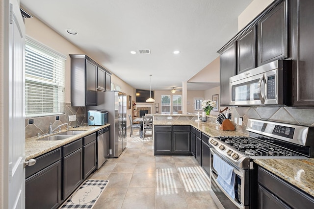 kitchen featuring pendant lighting, sink, light tile patterned floors, stainless steel appliances, and light stone countertops