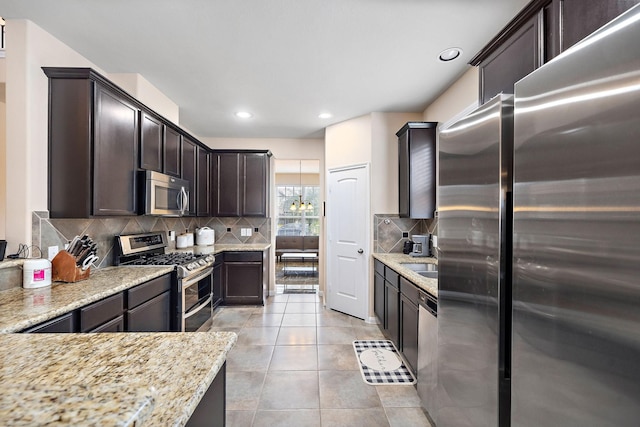 kitchen with light stone counters, light tile patterned floors, backsplash, and appliances with stainless steel finishes