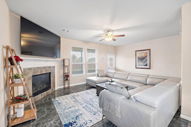 living room with ceiling fan and a tiled fireplace