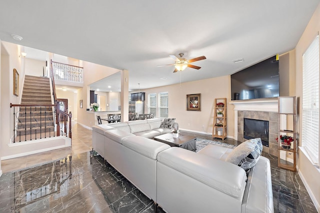 living room featuring a tiled fireplace and ceiling fan