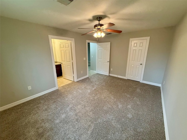 unfurnished bedroom featuring ensuite bathroom, light colored carpet, and ceiling fan