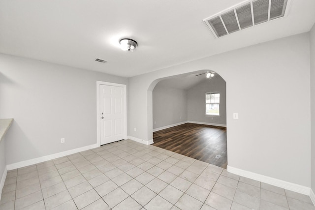 tiled spare room with ceiling fan and vaulted ceiling