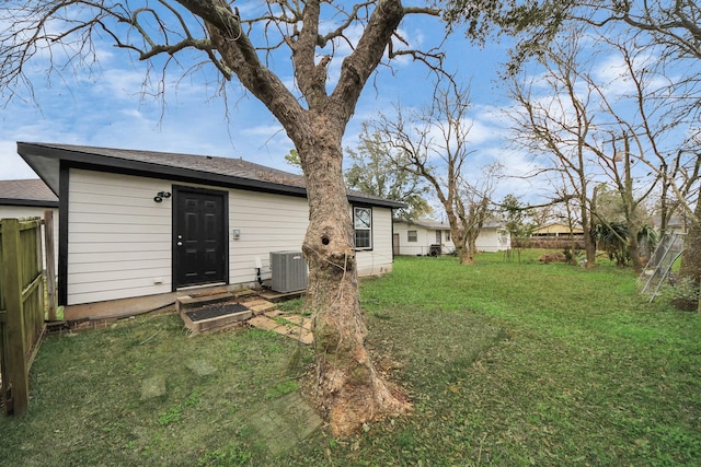 rear view of property with central AC unit and a lawn