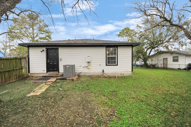 rear view of property featuring a lawn and central air condition unit