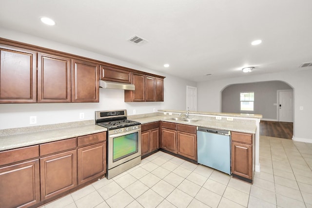 kitchen with stainless steel appliances, sink, light tile patterned floors, and kitchen peninsula