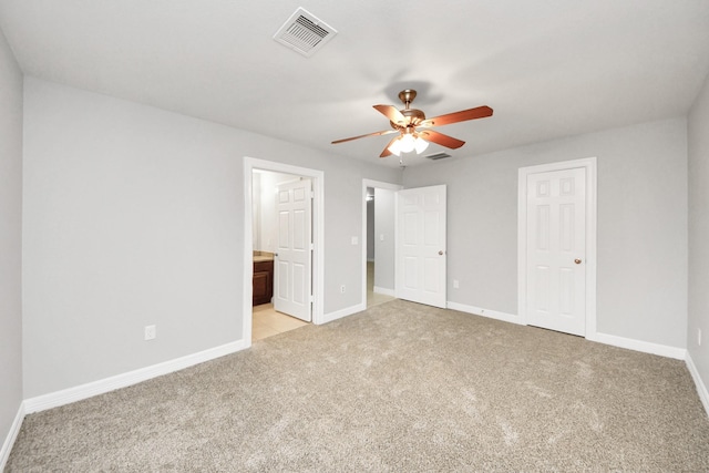 unfurnished bedroom with ceiling fan, light colored carpet, and connected bathroom