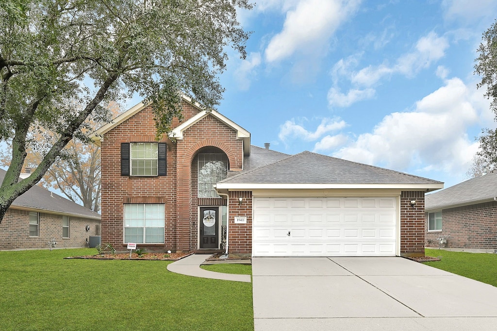 view of front facade with a garage, a front yard, and central AC unit