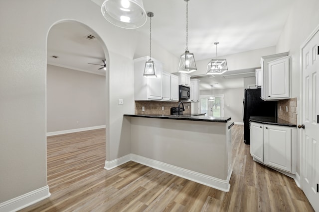 kitchen featuring decorative light fixtures, black appliances, kitchen peninsula, and white cabinets