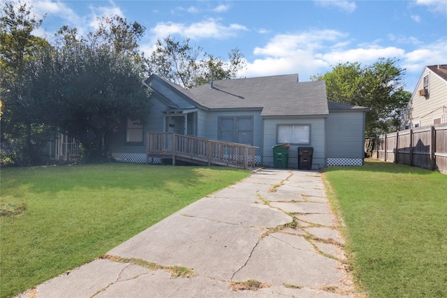 view of front of house with a deck, fence, a front lawn, and roof with shingles