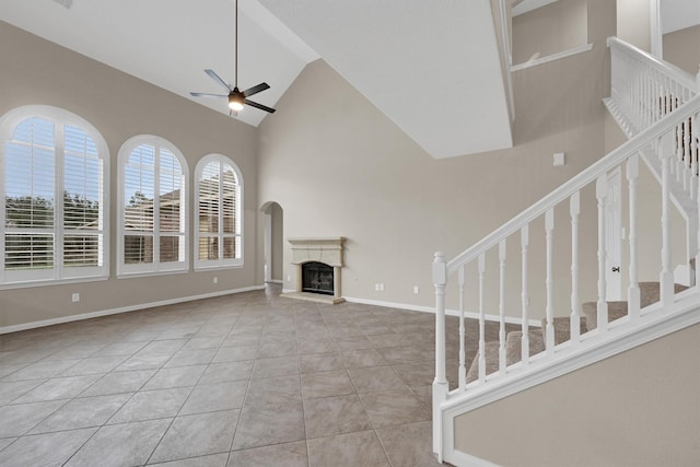 unfurnished living room with light tile patterned floors, high vaulted ceiling, and ceiling fan