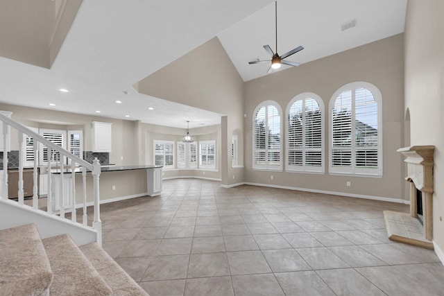 unfurnished living room with high vaulted ceiling, light tile patterned floors, and ceiling fan