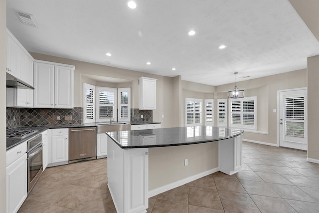 kitchen with tasteful backsplash, a center island, hanging light fixtures, stainless steel appliances, and white cabinets