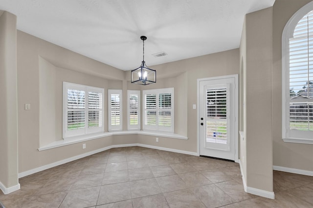 unfurnished dining area with a chandelier and light tile patterned floors