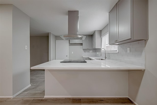 kitchen with gray cabinets, island range hood, tasteful backsplash, sink, and kitchen peninsula