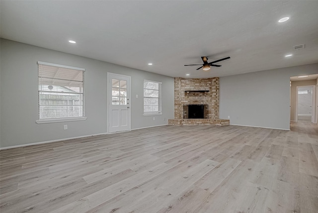 unfurnished living room featuring a brick fireplace, ceiling fan, and light wood-type flooring