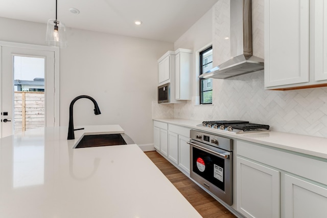 kitchen featuring wall chimney exhaust hood, stainless steel appliances, sink, and white cabinets