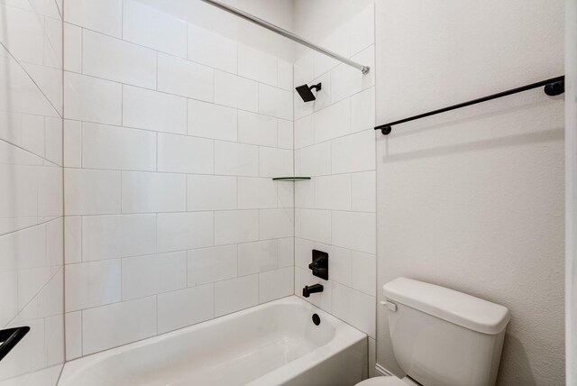 bathroom with tiled shower / bath combo and toilet