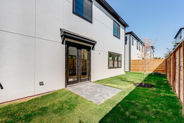 rear view of property with french doors, a patio, and a lawn