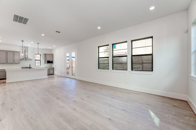 unfurnished living room with french doors, sink, and light wood-type flooring