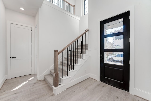 entrance foyer with a towering ceiling and light hardwood / wood-style flooring