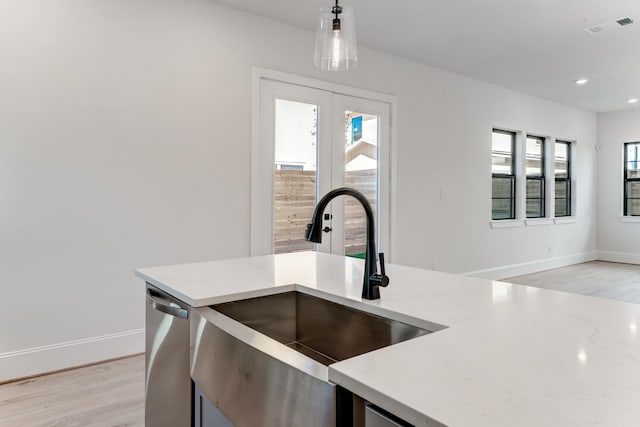 kitchen with pendant lighting, sink, light hardwood / wood-style flooring, stainless steel dishwasher, and french doors