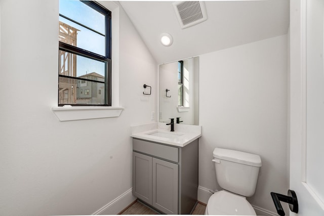 bathroom featuring lofted ceiling, vanity, and toilet