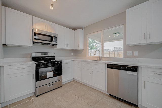 kitchen featuring sink, light tile patterned floors, appliances with stainless steel finishes, light stone countertops, and white cabinets