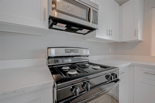 kitchen featuring white cabinetry, light stone countertops, and black gas range oven