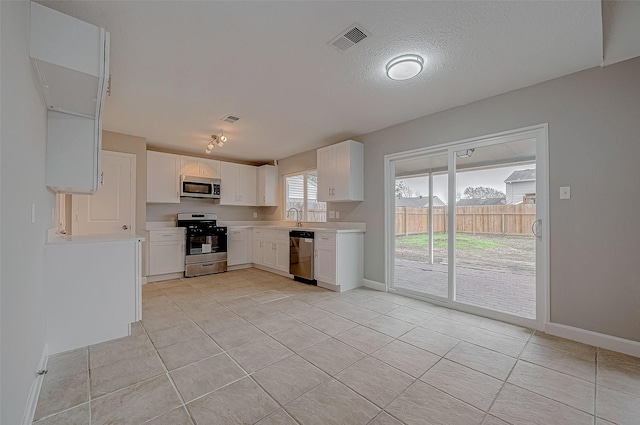 kitchen with appliances with stainless steel finishes, sink, a textured ceiling, and white cabinets