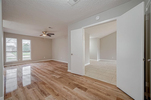 unfurnished room featuring ceiling fan, a textured ceiling, and light wood-type flooring