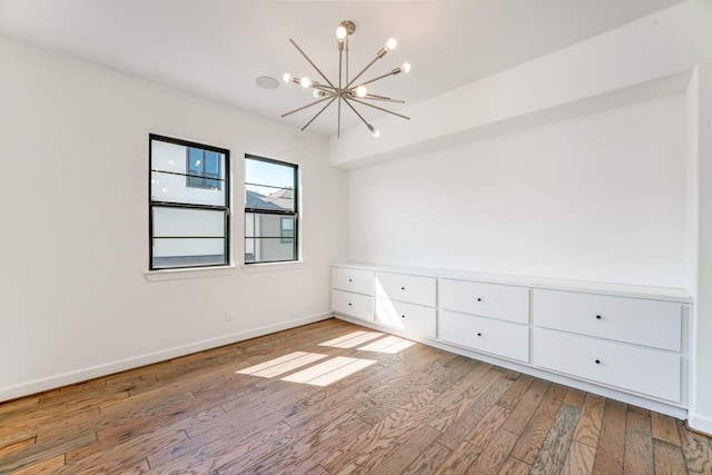 spare room with an inviting chandelier and light hardwood / wood-style floors