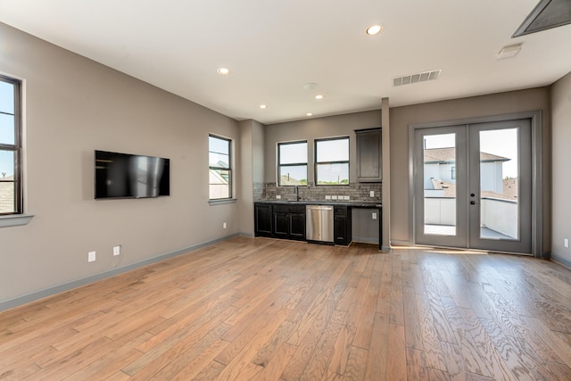 unfurnished living room with sink, light wood-type flooring, and french doors