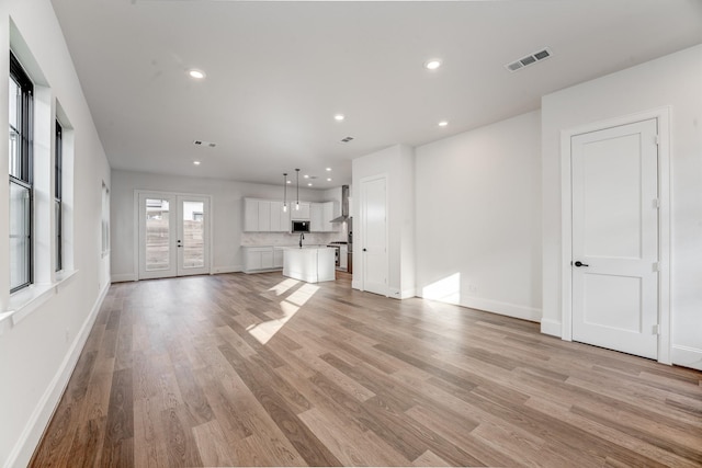 unfurnished living room featuring french doors and light wood-type flooring