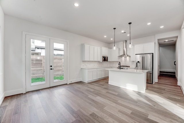 kitchen featuring hanging light fixtures, white cabinetry, high end refrigerator, and wall chimney exhaust hood