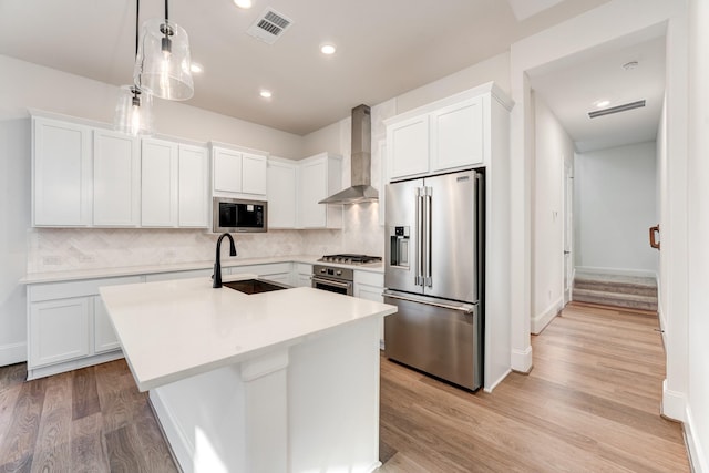 kitchen with white cabinetry, wall chimney range hood, sink, and appliances with stainless steel finishes