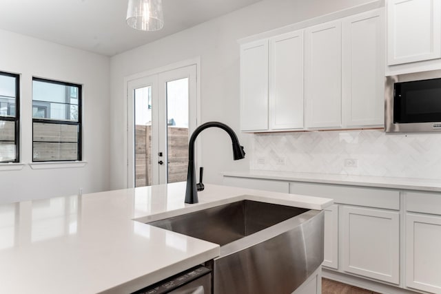 kitchen with built in microwave, sink, white cabinetry, hanging light fixtures, and backsplash