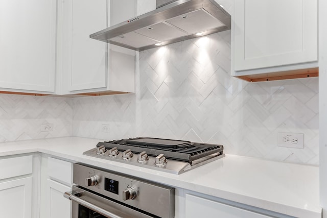 kitchen with tasteful backsplash, ventilation hood, white cabinets, and appliances with stainless steel finishes