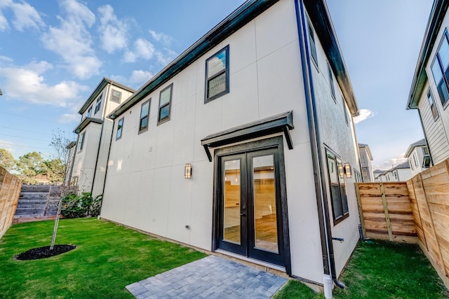 back of property with a yard and french doors